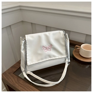 Close-up of white crossbody bag with delicate pink butterfly embroidery and chain strap