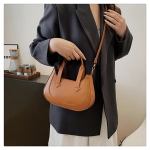 Brown PU leather crescent bag shown on model with shoulder strap and minimalist stitching