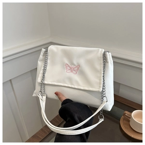 Close-up of a white shoulder bag with pink butterfly embroidery and silver chain strap
