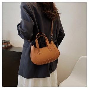 Close-up of brown crescent handbag with triangle stitching detail on high-quality leather