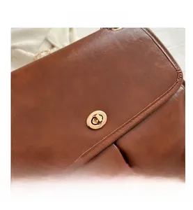 Detailed macro shot of vintage brown leather texture and golden metal twist lock on the bag