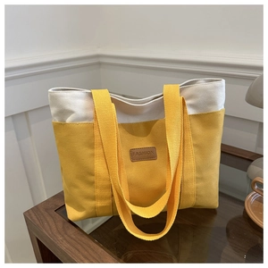 Détail du sac cabas en toile montrant le tissu patchwork jaune et beige et l'étiquette