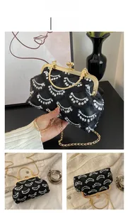 Detail of black sequin evening bag with gold metal frame and pearl-inspired ball clasp