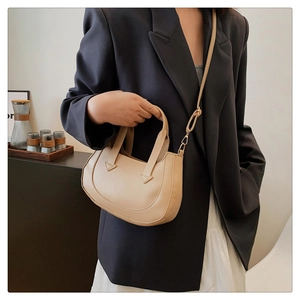 Minimalist beige crescent shoulder bag styled with elegant professional business attire