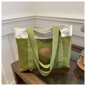 Détail du sac fourre-tout en toile verte et crème avec étiquette en cuir marron