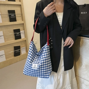 Détail du sac cabas en toile à carreaux bleu et blanc avec anses rouges et logo EMIS