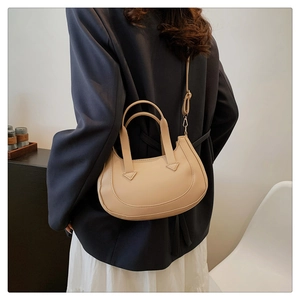 Model wearing a beige crescent shoulder bag with adjustable strap for daily commute