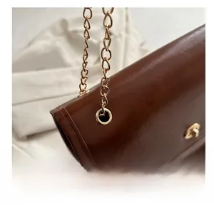 Detail of vintage brown chain bag showing glossy leather texture and gold turn-lock closure