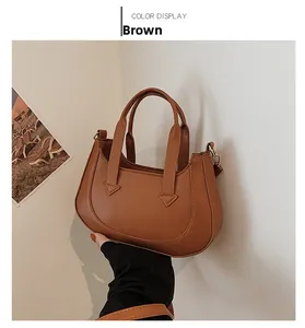 Detail view of brown matte leather crescent handbag with elegant top handles and hardware