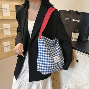 Détail du sac cabas à carreaux bleu et blanc avec bandoulière rouge et logo EMIS