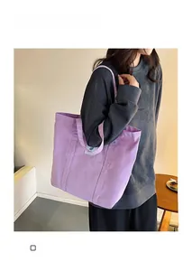 Detailed view of light purple canvas tote bag with shoulder straps worn by model