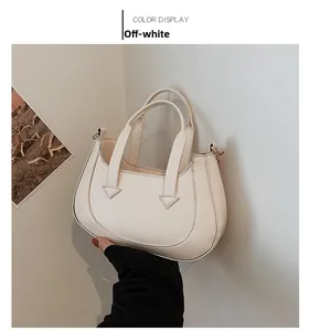 Detail of off-white crescent handbag showing the smooth PU leather and top handles