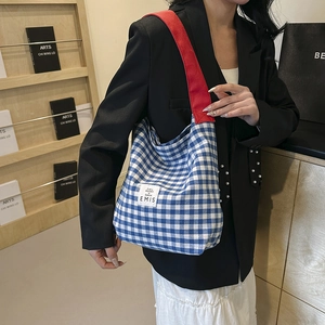 Détail du sac cabas à carreaux bleu et blanc avec large bandoulière rouge et logo