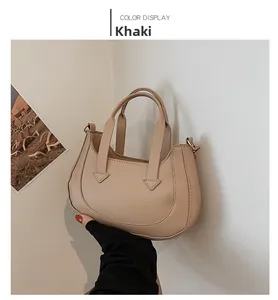 Detail of khaki crescent handbag showing smooth matte leather texture and metal strap rings