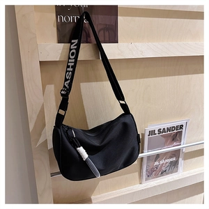 Détail du sac en nylon noir avec bandoulière à logo FASHION et pendentif tressé