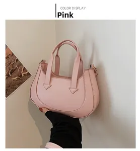 Detail showing the pink crescent handbag's inverted triangular stitching and dual handles