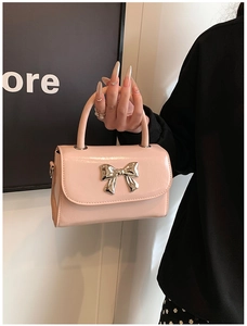 Detail of pink faux leather handbag showing elegant silver metal bow buckle and top handle