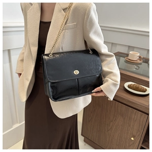 Detail of a vintage black patent leather shoulder bag with a gold metal ring lock