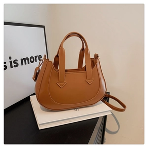 Detailed macro view of the caramel PU leather texture and arrow metal hardware on the handbag
