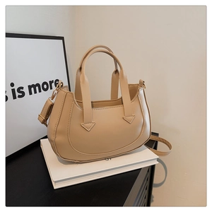 Detail of light beige crescent handbag with smooth leather texture and gold hardware