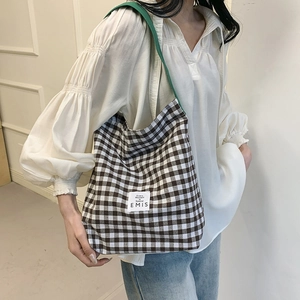 Gros plan du sac fourre-tout à carreaux marron montrant la texture et la sangle verte