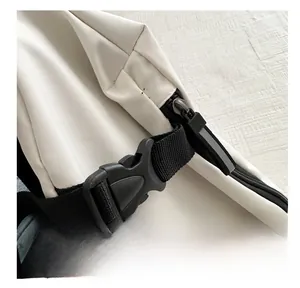 Detalle de la hebilla de plástico negro y la correa de nailon en el bolso bandolera blanco