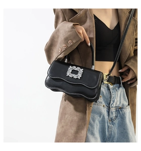 Détail du sac à bandoulière en cuir noir avec bords ondulés et boucle carrée en cristal