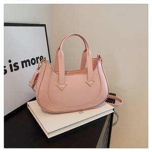 Detail view of pink crescent moon bag with golden hardware on white art setup