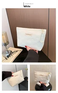 Detailansicht der weißen Kosmetiktasche mit Herzprägung, Perlengriff und Mode-Label