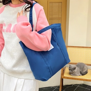Detail of a navy blue canvas tote bag featuring a white side label and wide shoulder strap