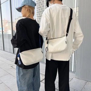 Sac bandoulière minimaliste demi-lune en cuir noir et blanc avec breloque tissée