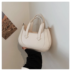 Detail view of cream white crescent handbag showing matte PU leather texture and handles