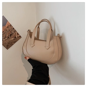 Detail of beige crescent shoulder bag with triangular stitching and metal hooks