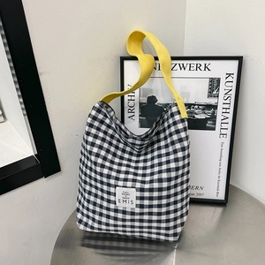Détail du sac cabas en toile à damier noir et blanc avec une large bandoulière jaune vif