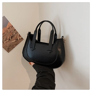 Detail of the black crescent shoulder bag featuring reinforced handles and sleek synthetic leather
