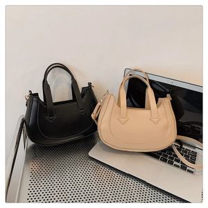 Close-up of black and beige crescent bags with adjustable straps on a display rack