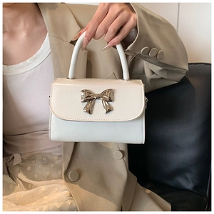 Detail of white mini handbag with silver metallic bow buckle and precise stitching