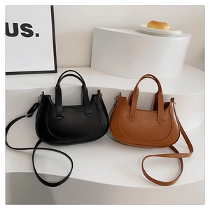 Detail showing minimalist black and brown half-moon handbags with double top handles