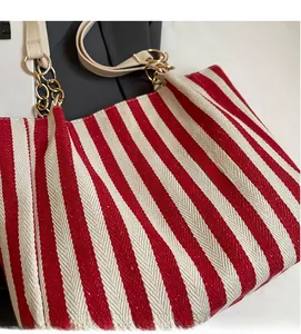 Close-up of red and white striped woven tote bag with gold chain and leather handle