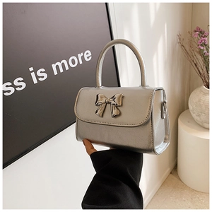 Macro shot of silver square handbag featuring a metallic bow and top handle