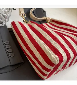 Detailed close-up of red and white striped canvas tote bag with gold metal hardware