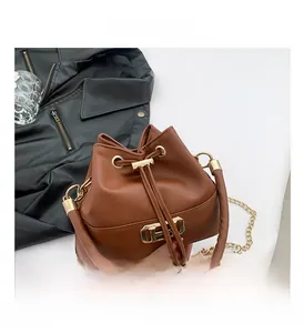 Detail view of brown bucket bag with gold square hardware and drawstring closure