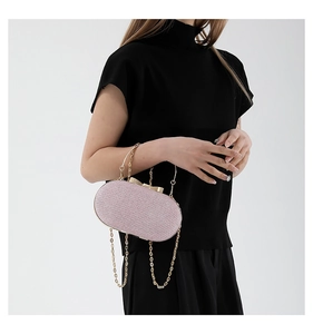 Close-up of pink glitter evening clutch bag with gold bow clasp and chain strap