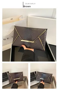 Detail of a brown crocodile pattern envelope clutch with elegant gold metal trim