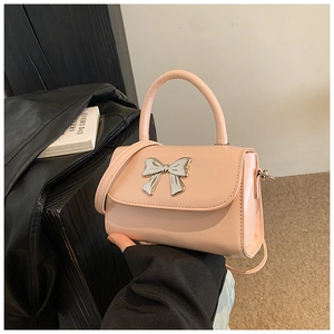 Close-up of pink mini crossbody bag with metallic silver bow and polished finish