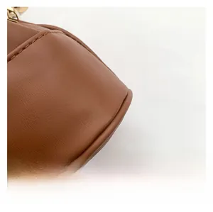 Close-up of brown PU leather bucket bag showing fine texture and golden metal hook