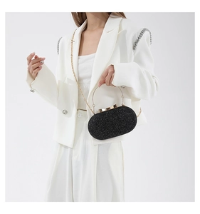 Close-up of black glitter evening clutch featuring metallic handle and gold chain strap