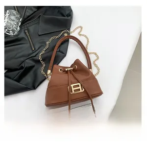 Detail of a brown leather drawstring bucket bag with a golden H metal clasp and chain