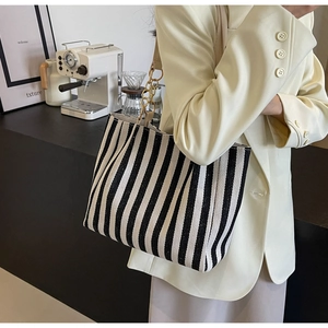 Detail showing black and white vertical stripes and gold metal chain strap on tote bag