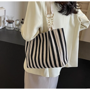Detail of the black and white vertical striped tote bag with gold metal chain strap